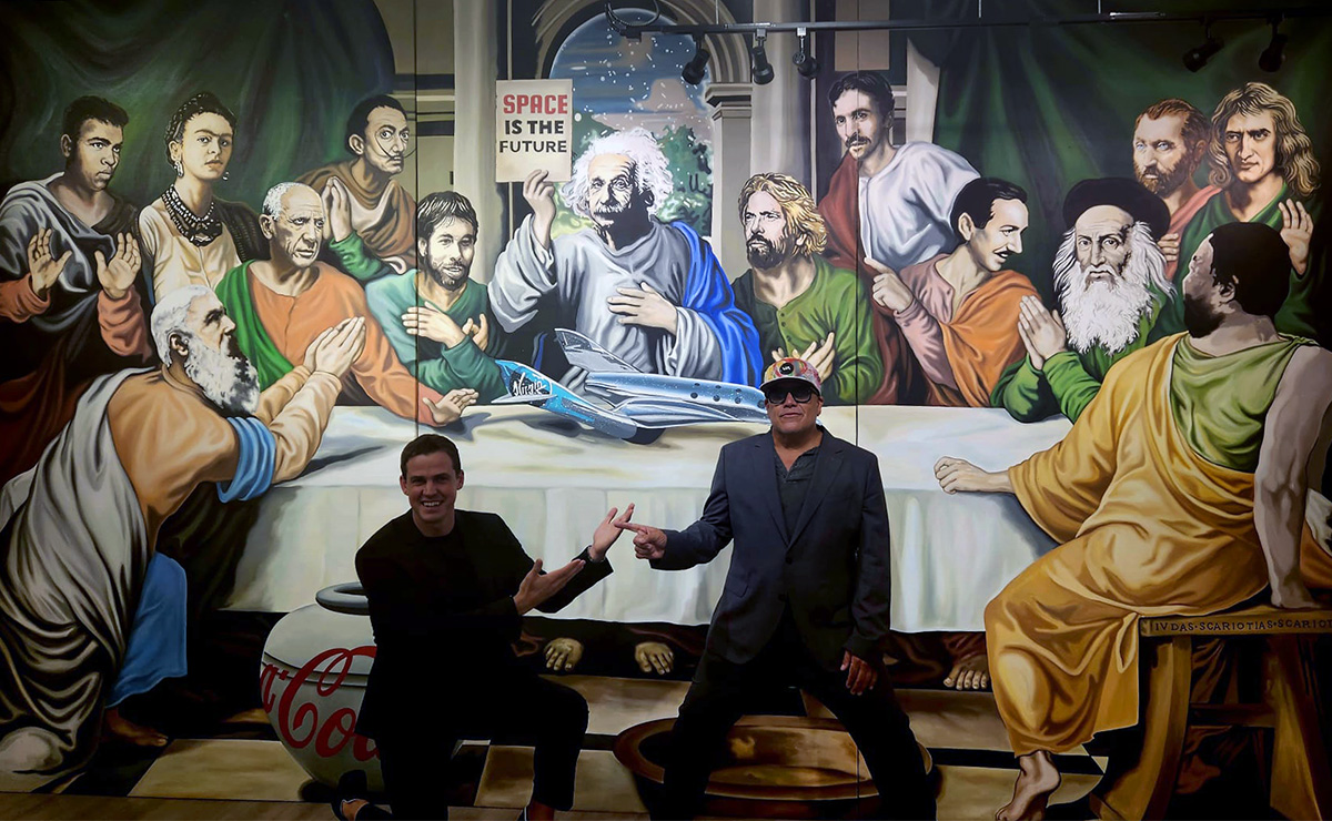 Artist Leonardo Hidalgo and tennis player Vasek Pospisil point to each other in mutual praise as they unveil a mural of famous figures from science, arts and technology gathered around a large table.